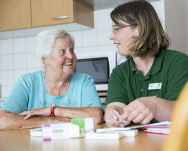 Seniorin und Pflegefachkraft am Tisch